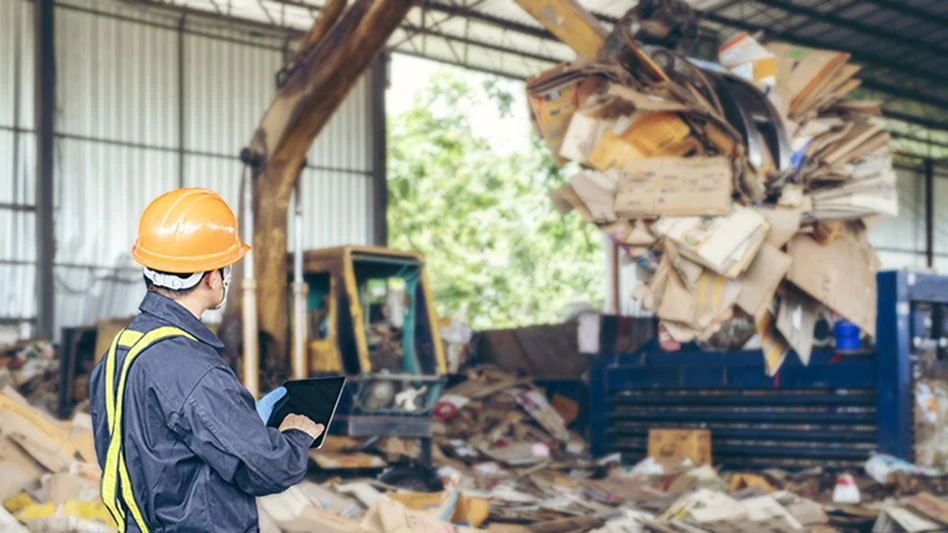 man watching material handler load bin in transfer station