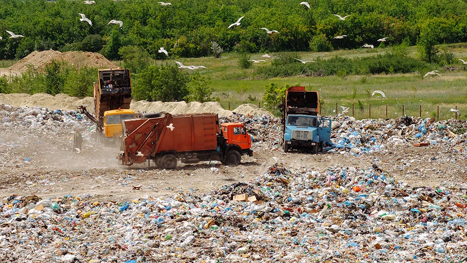 two trucks driving on a landfill site