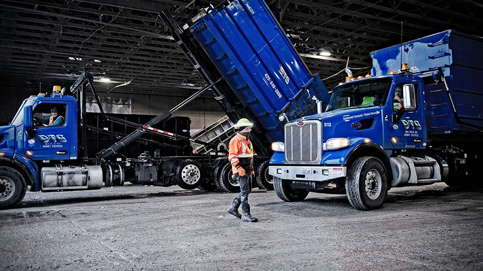 Man walks in front of DTG Recycle dump trucks