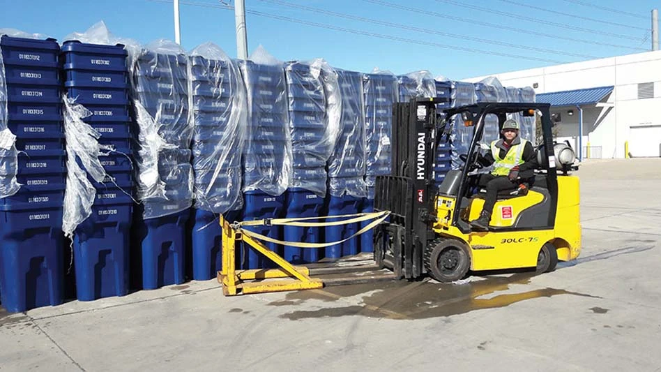 forklift in front of stacks of recycling carts