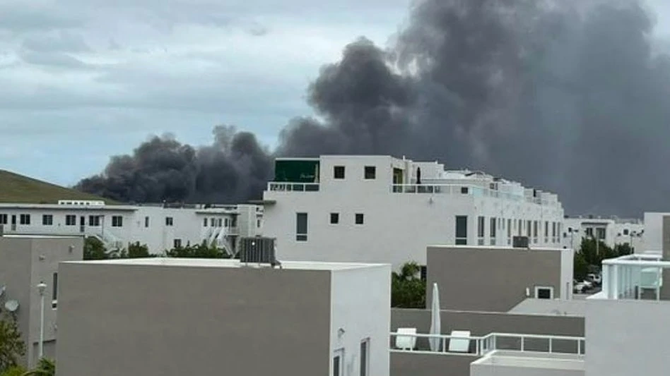 gray smoke billows over white buildings