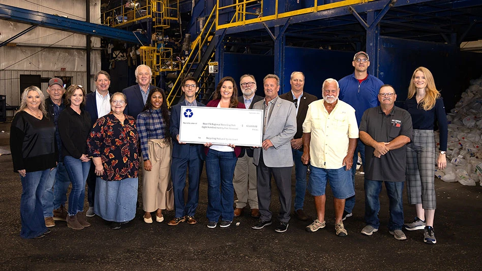 a group of people infront of a MRF catwalk hold a large check