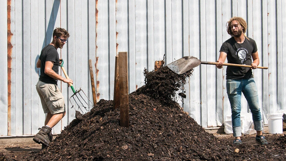 two men agitate and aerate compost pile