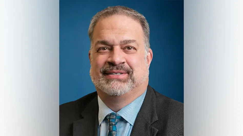 white man with goatee in blue button down and grey suit smiles for headshot