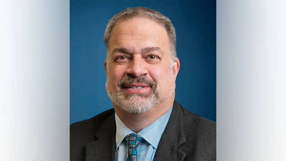 white man with goatee in blue button down and grey suit smiles for headshot