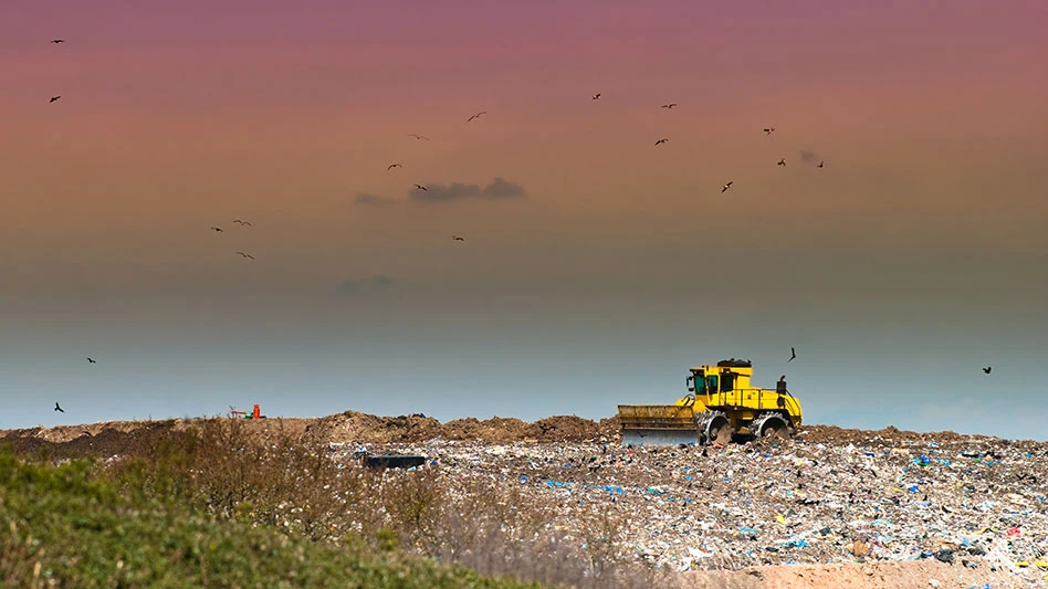 landfill compactor on landfill face during sunset