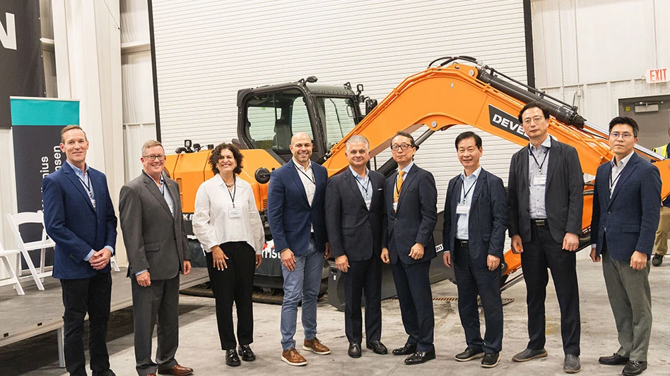 photo of executives standing in a row in front of construction equipment