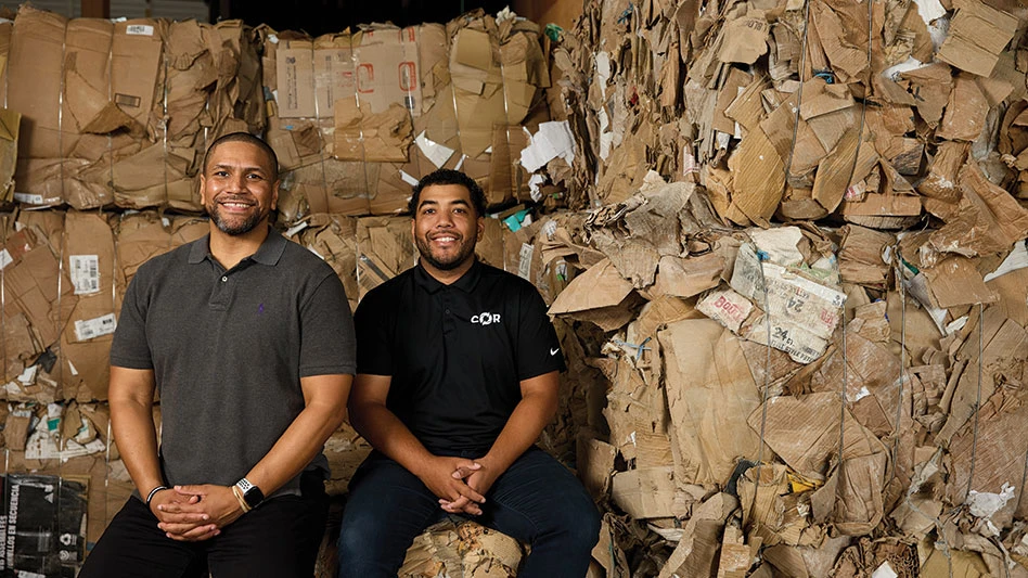 two black men in recycling facility smiling