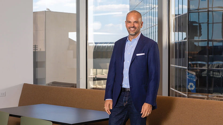 Smiling bald man standing in front of a window