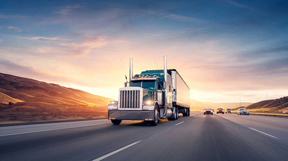 American style truck on freeway pulling load.